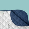 Close up of quilted corner of blanket showing blue fabric and dinosaur pattern on white background