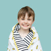Happy boy with lightning bolt blanket wrapped around him looking cosy, on an aqua background